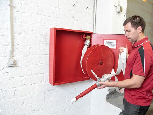 Das Bild zeigt einen Brandschutztechniker bei der Überprüfung einer Löschwasserleitung